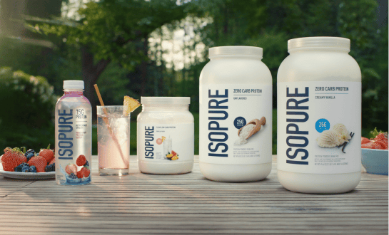 Assorted Isopure protein drinks and protein powder containers displayed outdoors with fresh berries and a prepared protein shake.